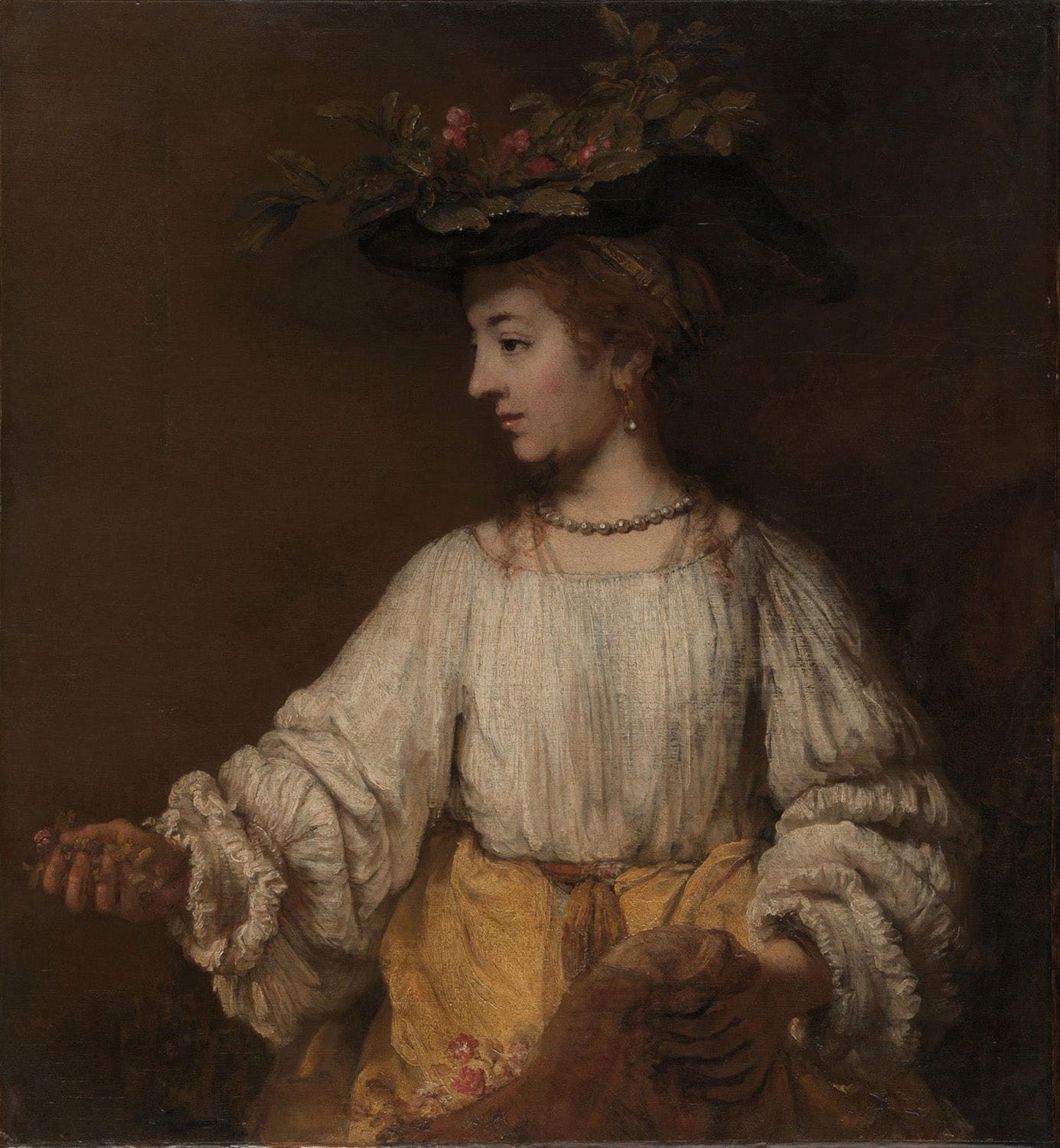 Flora, gemalt von Rembrandt van Rijn, zeigt eine Frau in barocker Kleidung mit Blumenschmuck, umgeben von warmen Farbtönen und einem sanften Licht-Schatten-Kontrast.