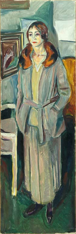 Stehende Frau in grauem Mantel mit Pelzkragen vor Stuhl und Wand – Edvard Munch Frau in Grau Kunstkopie