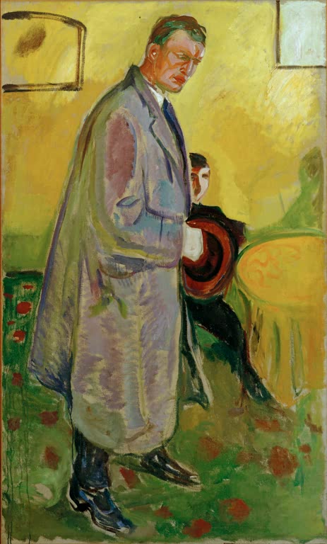 Mann im langen Mantel mit Hut in der Hand vor gelber Wand – Edvard Munch Selbstbildnis mit Mantel und Hut Kunstkopie